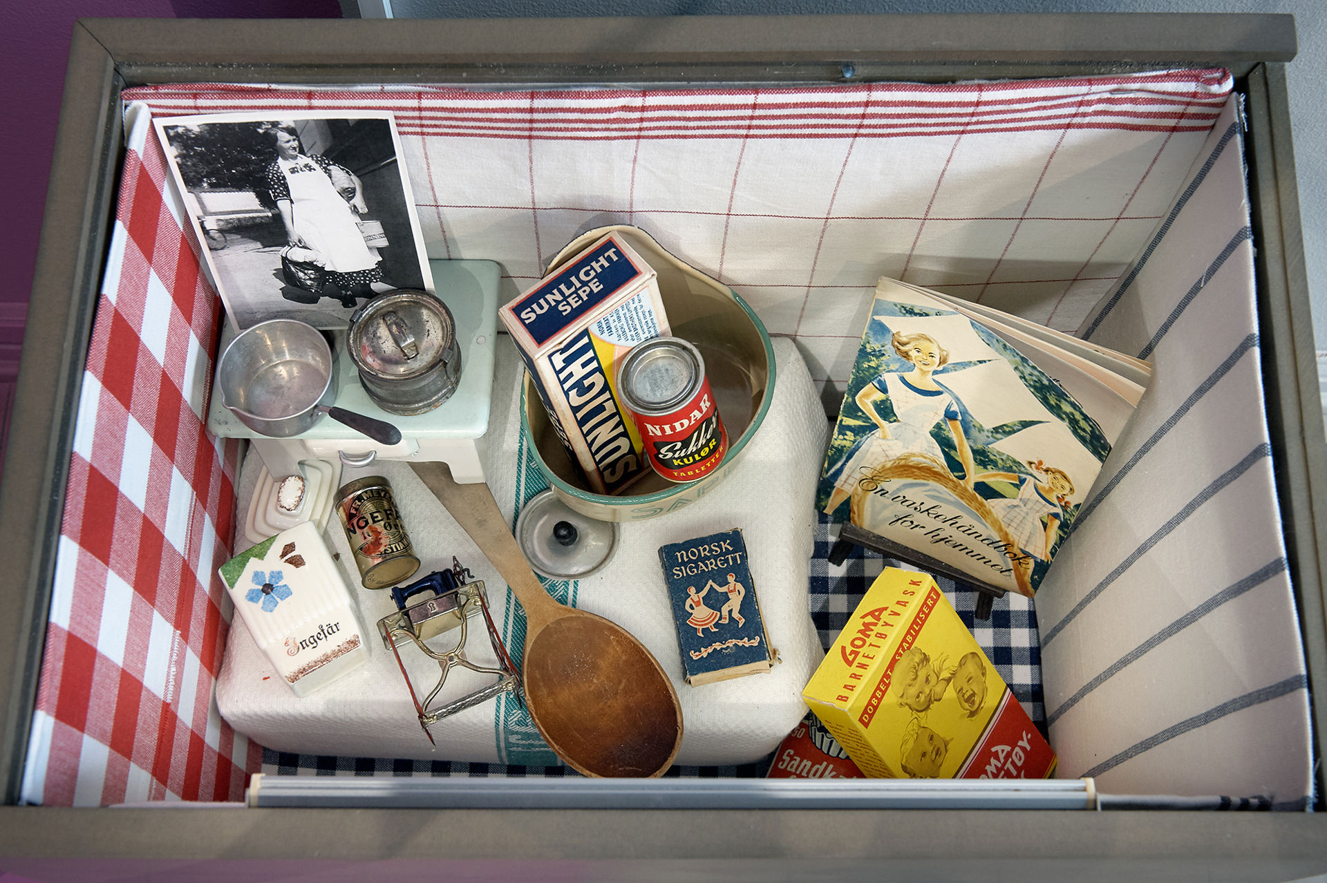 Kasse med gamle kjøkkenredskaper i tillegg innholder kassen blant annet såpe, sigarettpakke og en gammel vaskehåndbok.