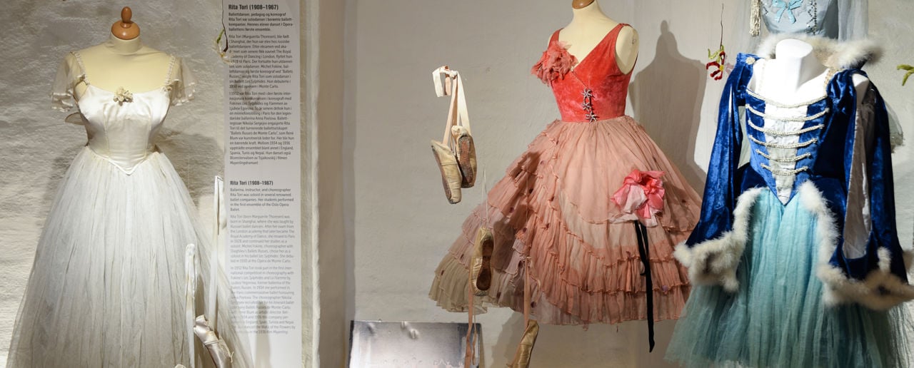 Fire ulike ballettkjoler og kostymer. Ballettsko både henger mellom kjolene og ligger på gulvet.