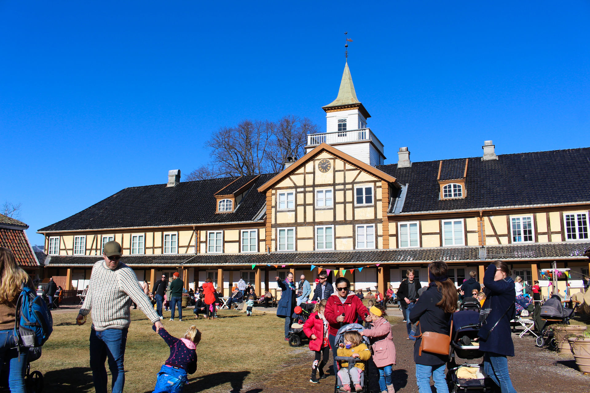 Barnefamilier i solskinnet på tunet til gamle Frogner hovedgård.