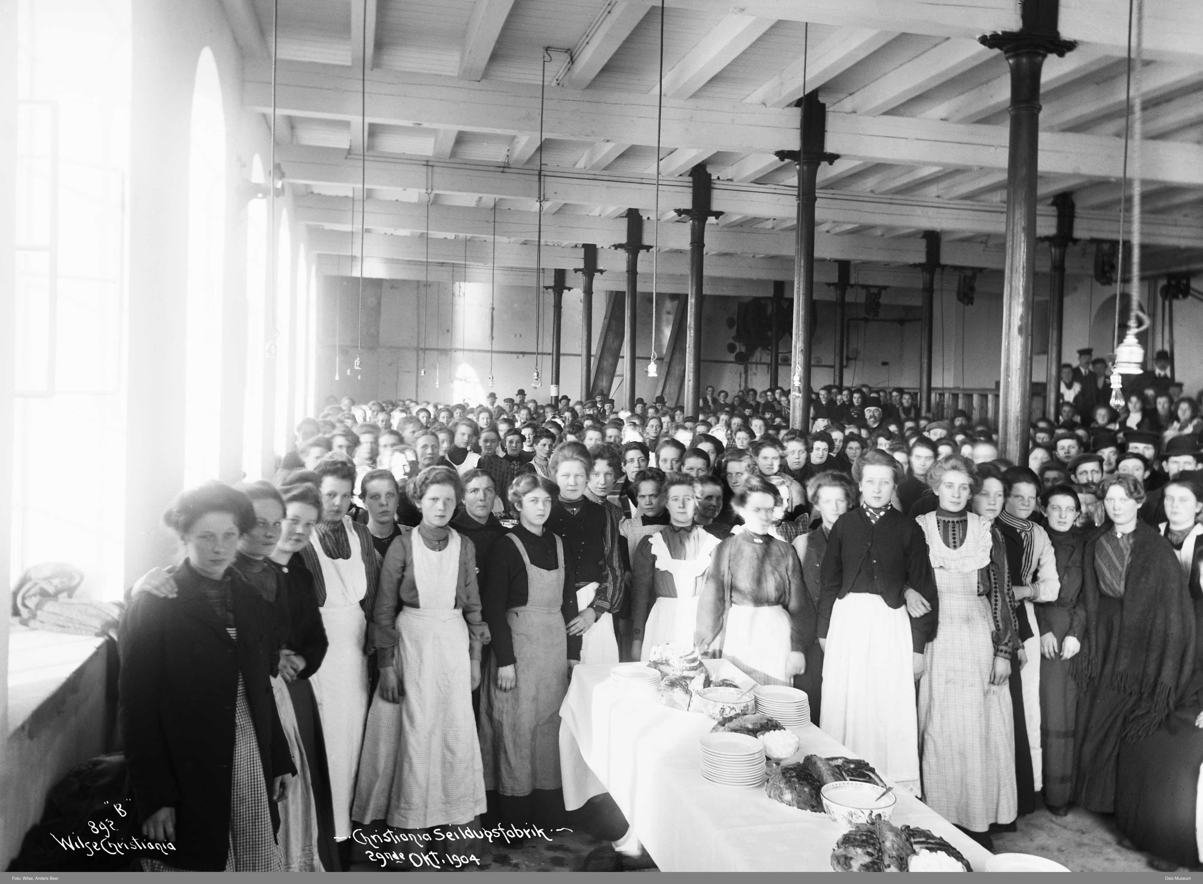 sorthvitt-bilde av kvinnelige arbeidere i forklær på en fabrikk