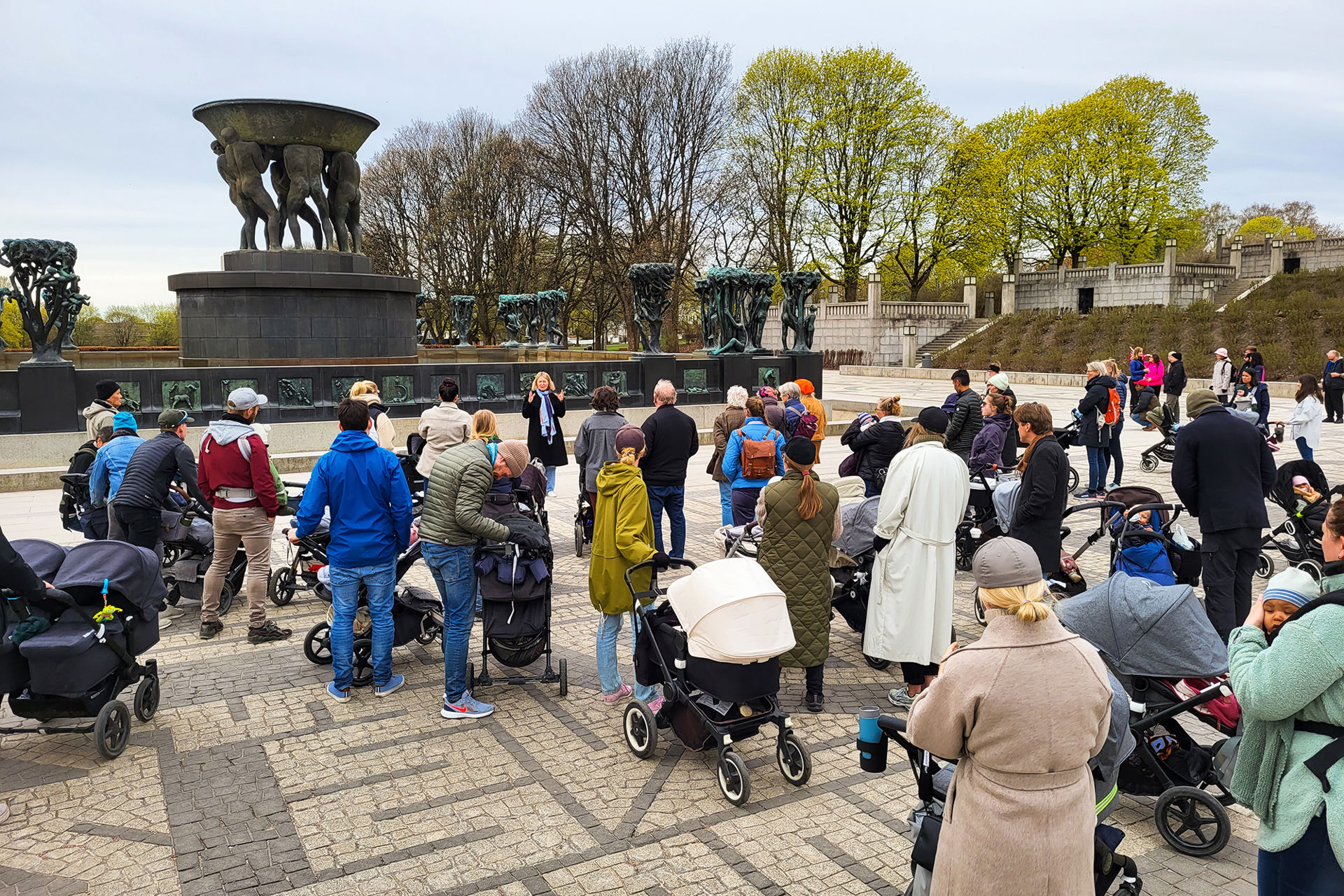 Mange mennesker med barnevogn på en åpen  plass.