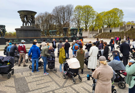 Mange mennesker med barnevogn på en åpen  plass.