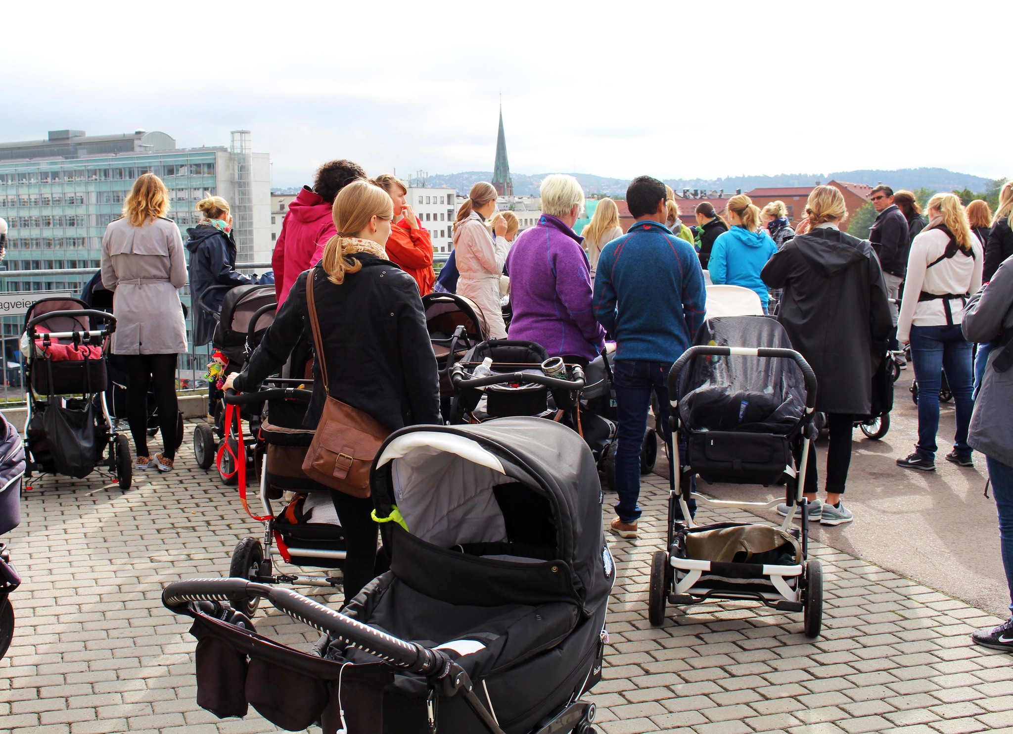 Personer med barnevogn utendørs i Oslo sentrum med ryggen til