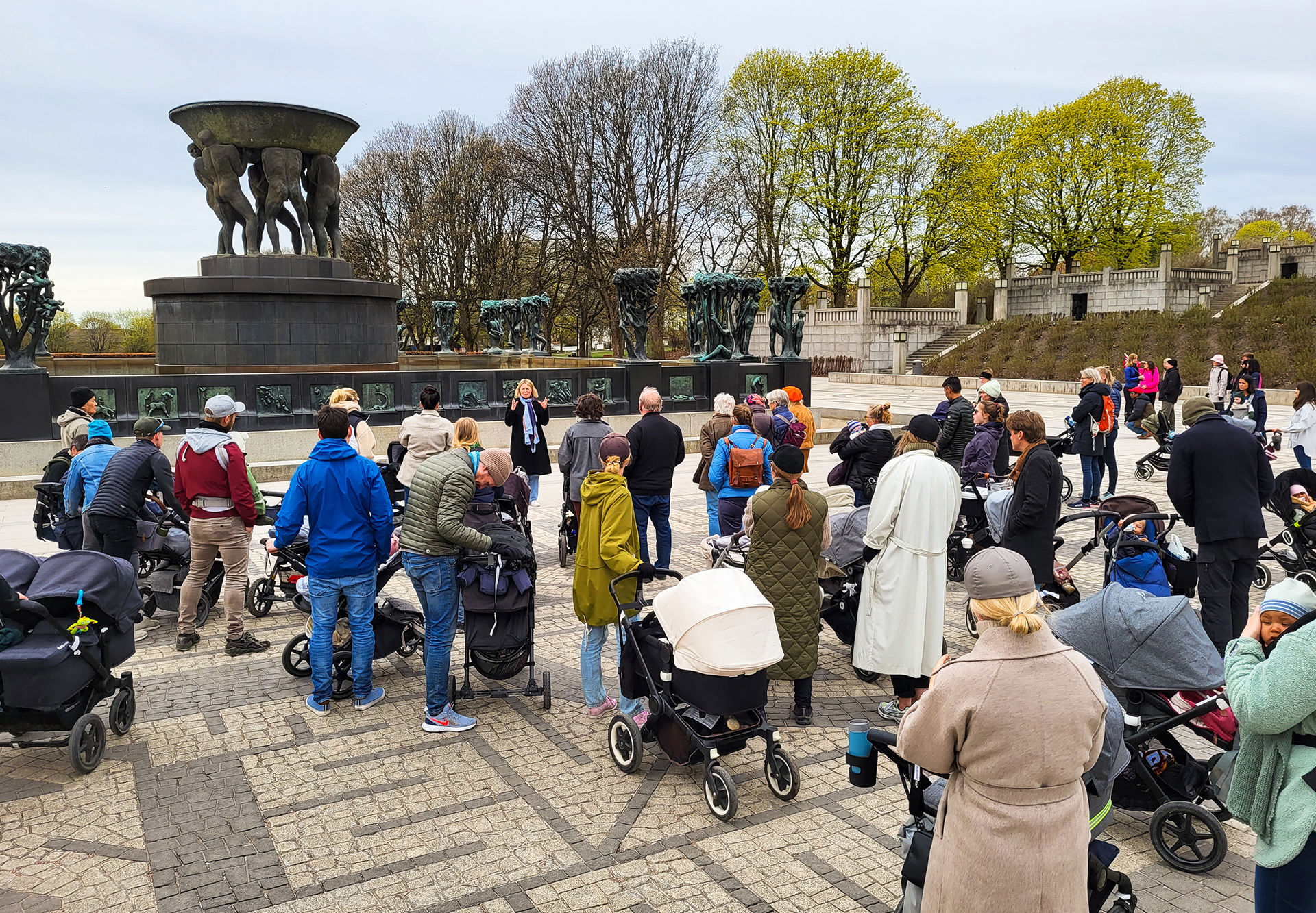 Mange mennesker med barnevogn på en åpen  plass.