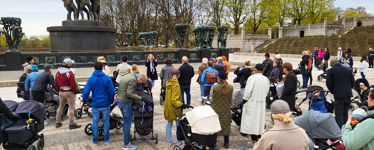 Mange mennesker med barnevogn på en åpen  plass.