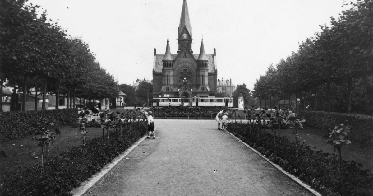 sorthvitt av symmetrisk park med trær på begge sider og en stor kirke i midten