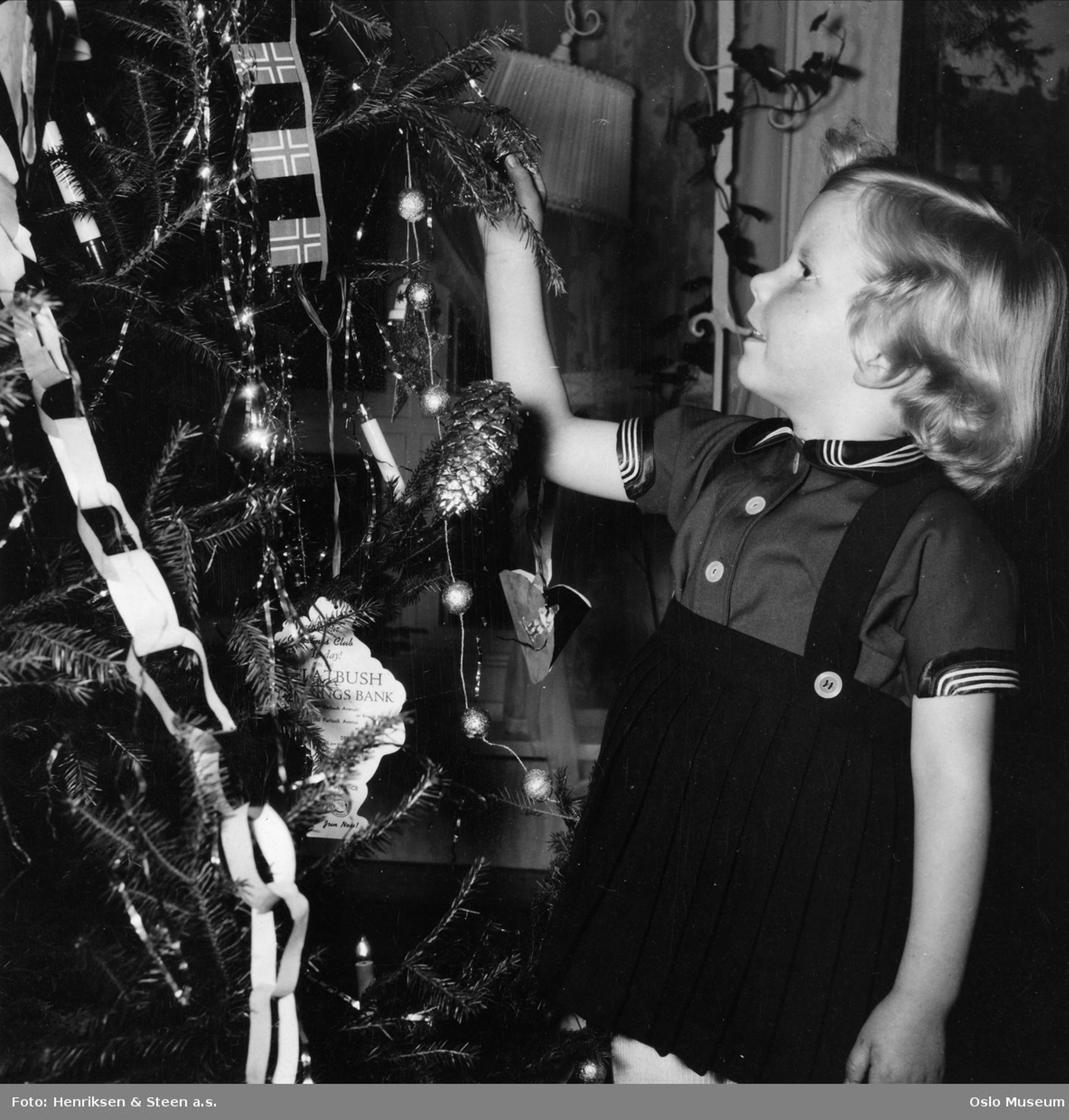 Sort-hvitt-bilde av ei jente som ser opp på et juletre