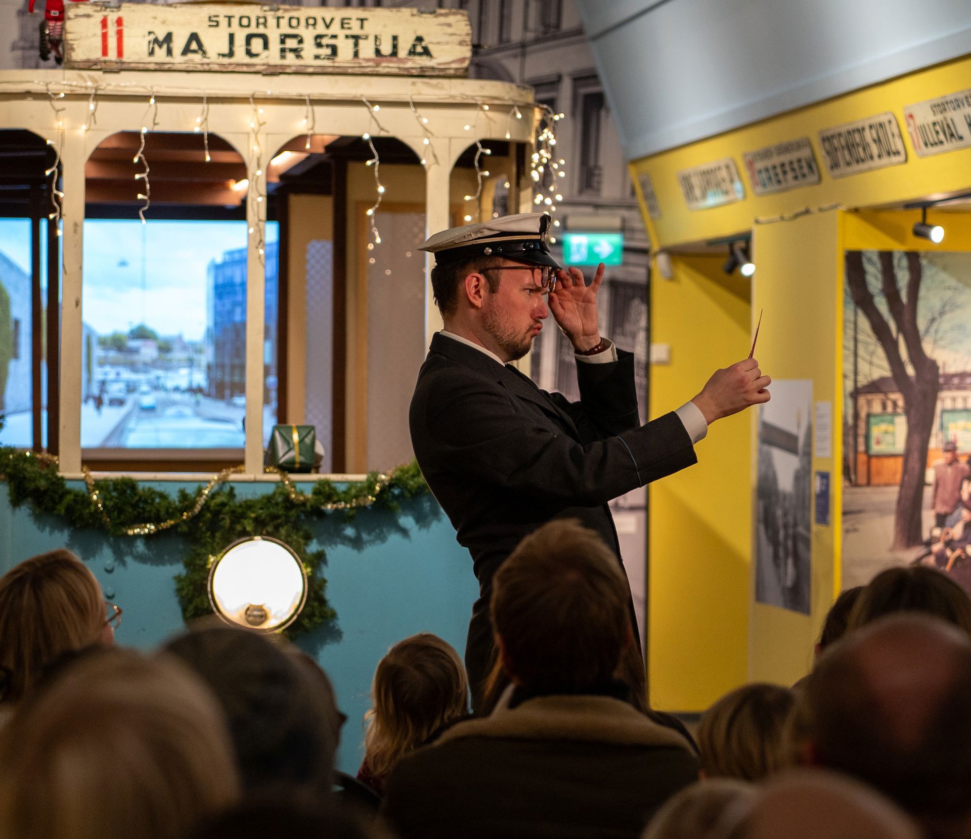 Mann i trikkeførerkostyme leser et brev foran en modelltrikk 