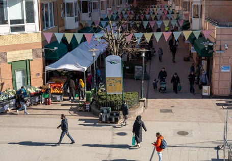 oversiktsbilde over grønland torg med mennesker, grønnsaksboder og vimpler over gata