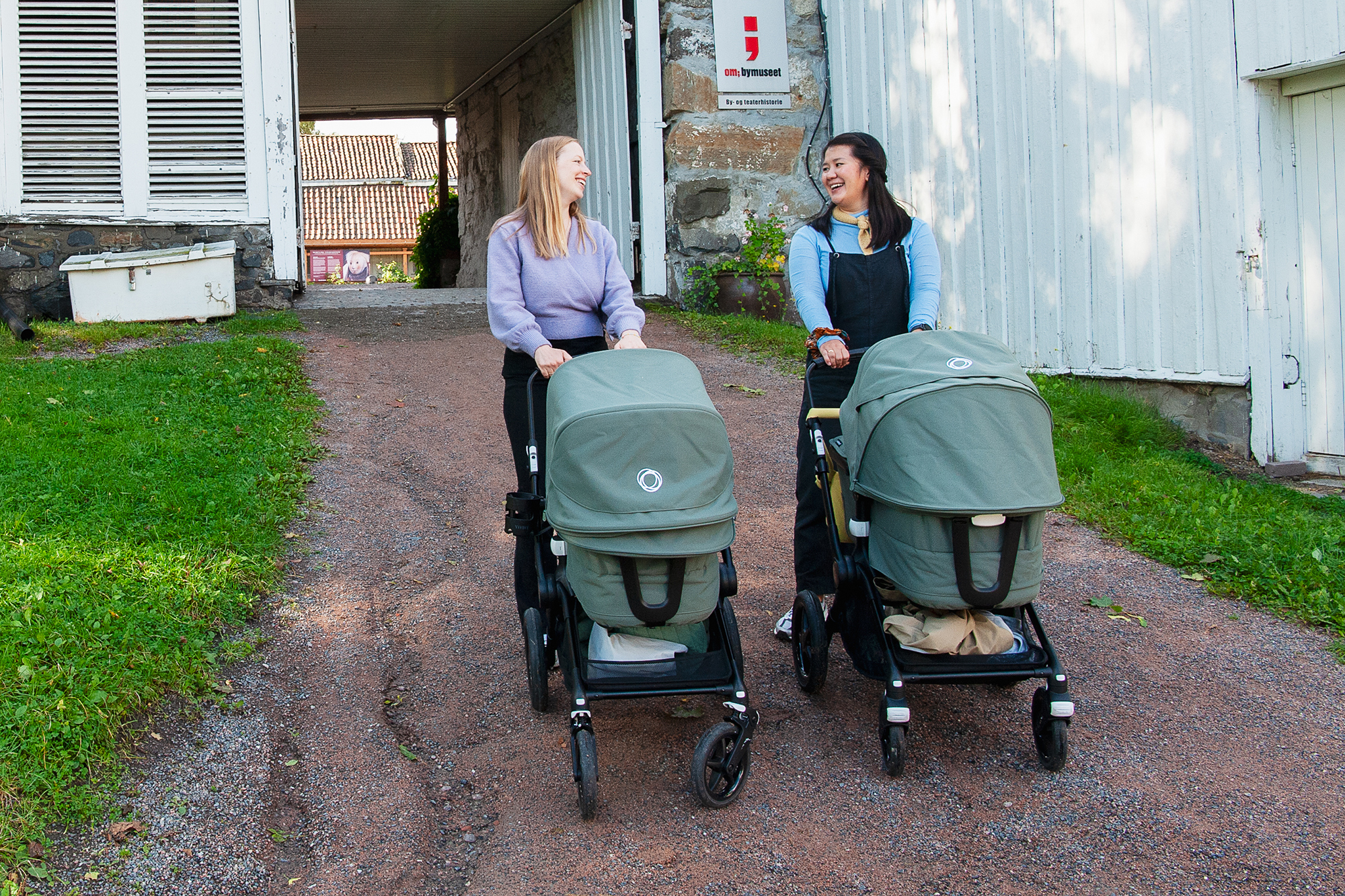 To mødre triller hver sin barnevogn. Porten til Frogner hovedgård i bakgrunnen.
