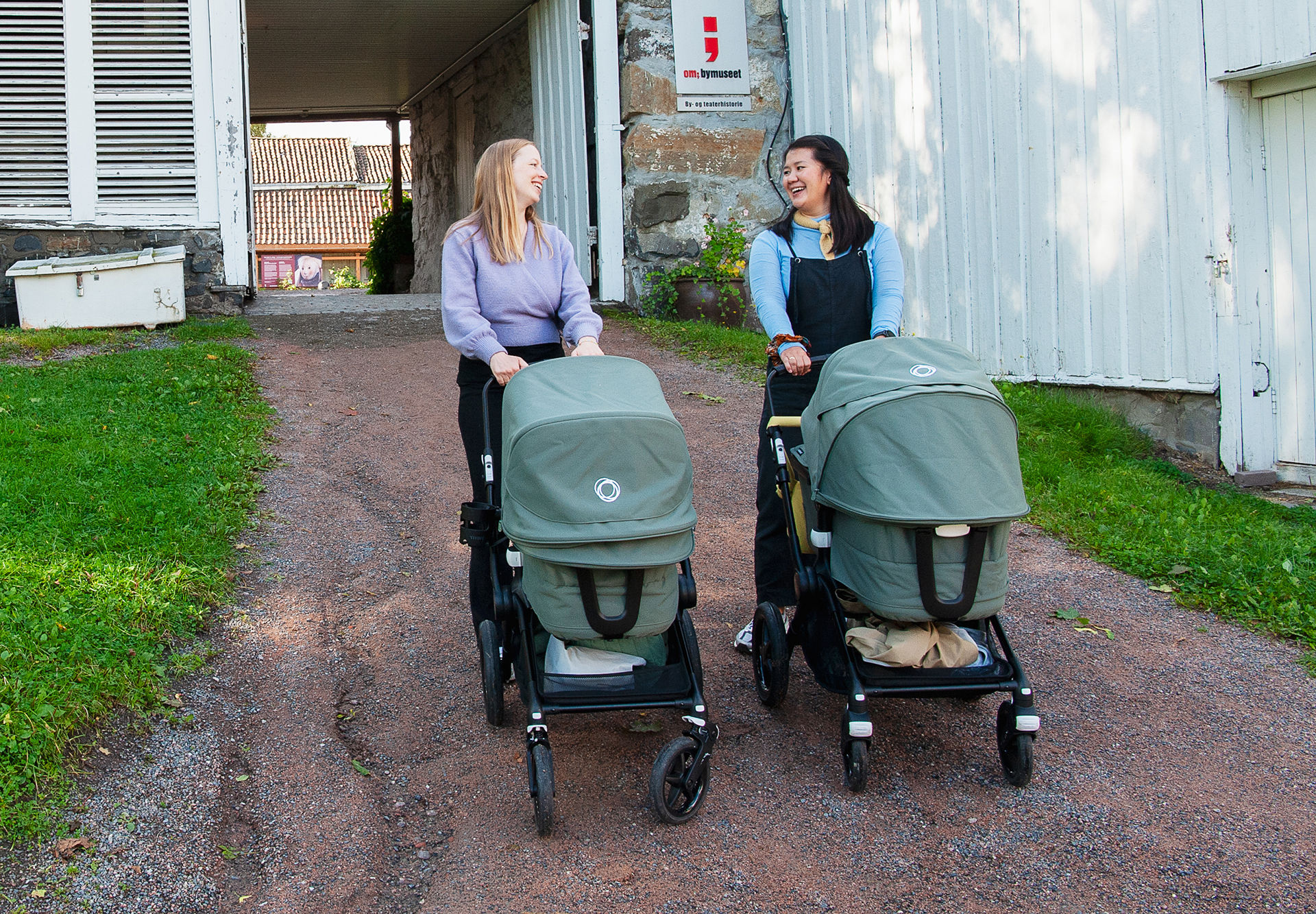 To mødre triller hver sin barnevogn. Porten til Frogner hovedgård i bakgrunnen.