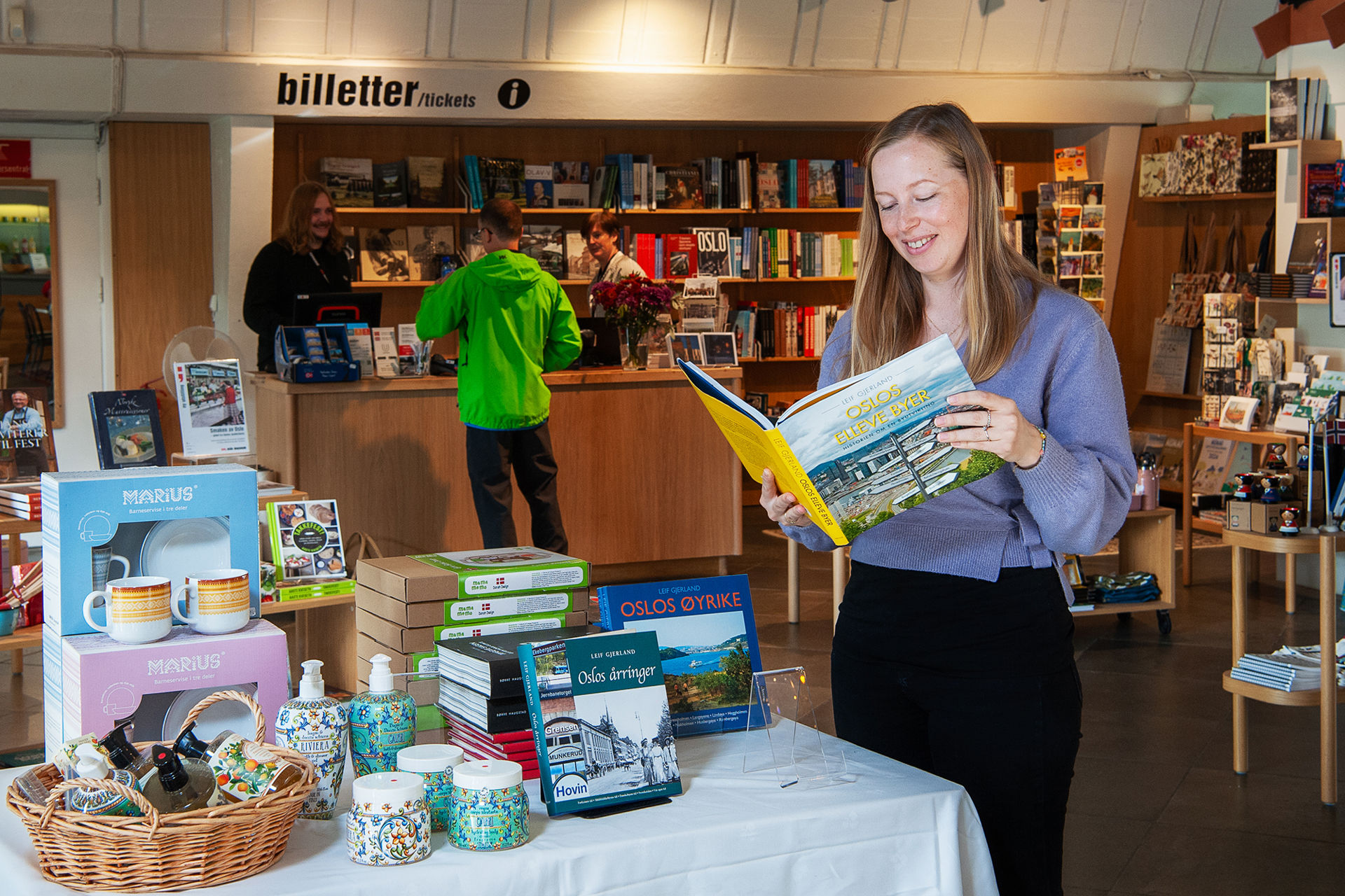 Kunde leser i en stor bok i museumsbutikken.