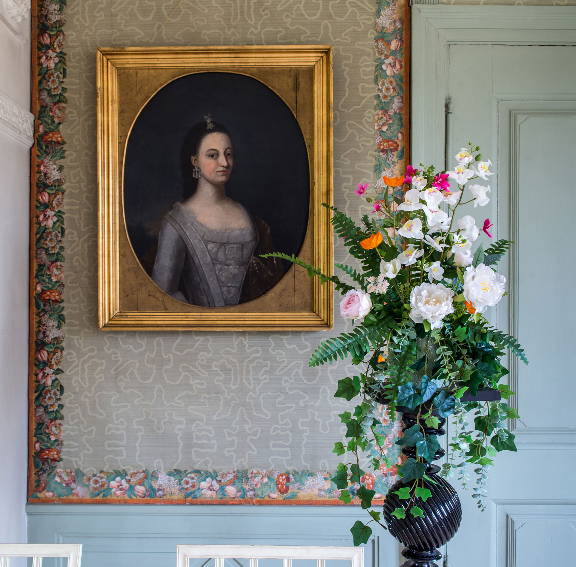 Blomsteroppsats og et gammelt portrett av en ung kvinne.