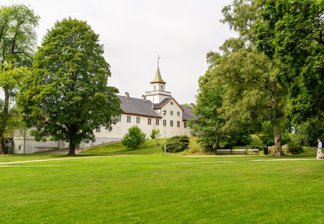 Grønn plen og Frogner hovedgård sett fra utsiden. Overskyet.