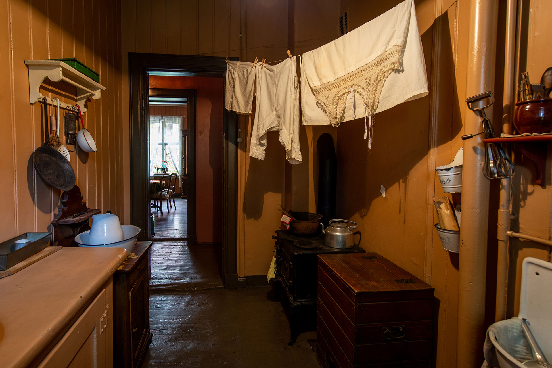 Utslagsvask, tøyvask henger på en snor, stekepanne og øser henger på veggen.