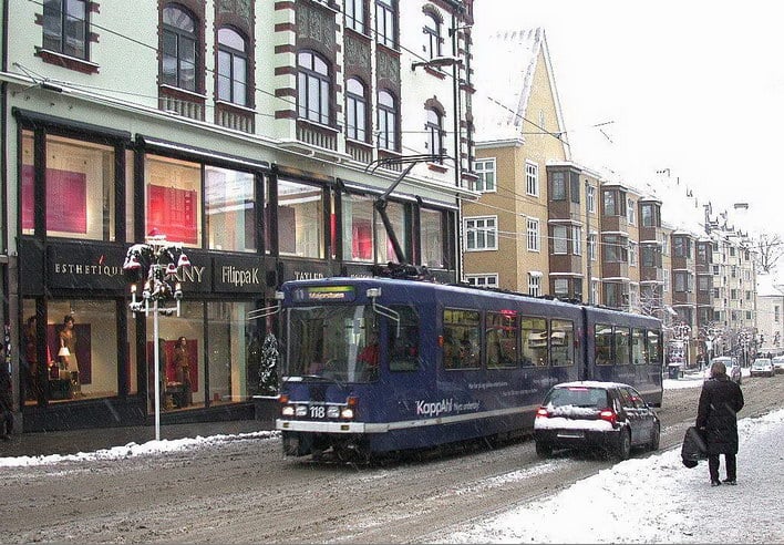 Handlegate med butikker og en trikk som kj&oslash;rer forbi