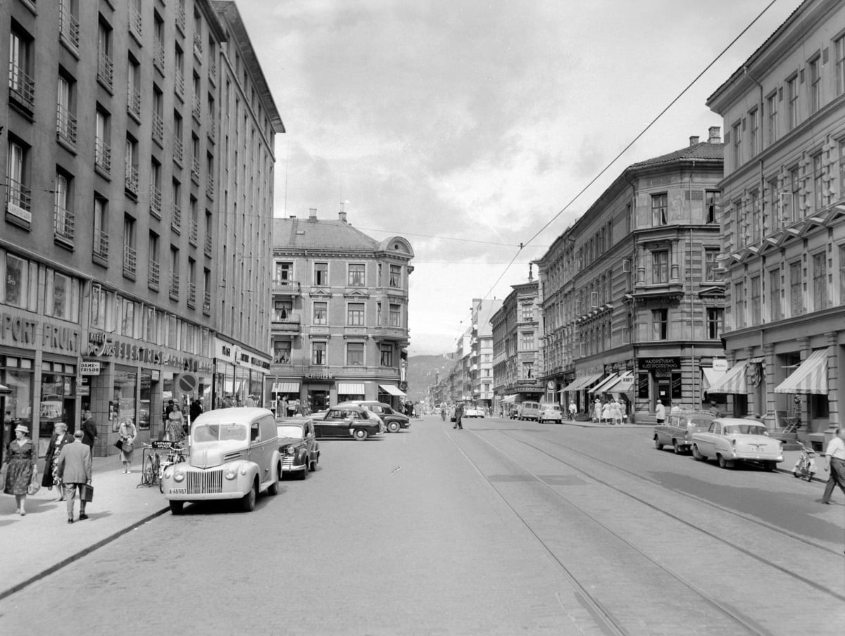 Gate med trikkeskinner, gamle biler og bygninger p&aring; begge sider