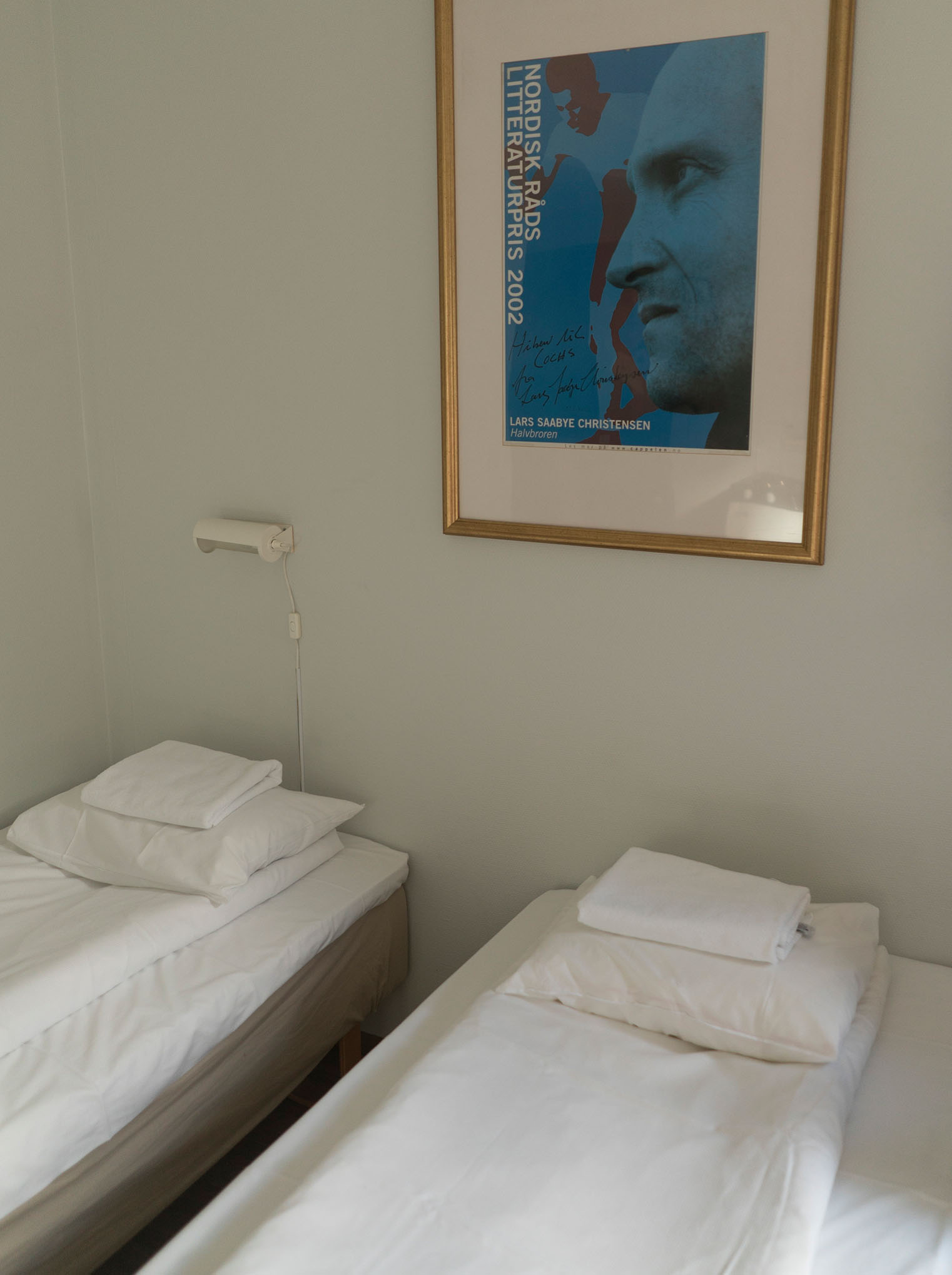 Beds in a room in Cochs Pensjonat with a framed picture of Lars Saabye Christensen on the wall