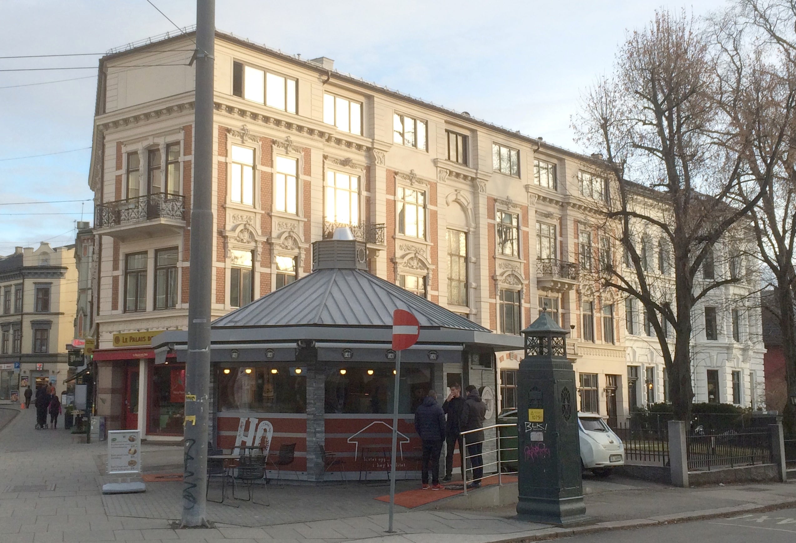 Hj&oslash;rnebyg&aring;rd med flotte utsmykninger men en enklere fasade i &oslash;verste etasje. Mindre flerkantet bygg i forgrunnen.