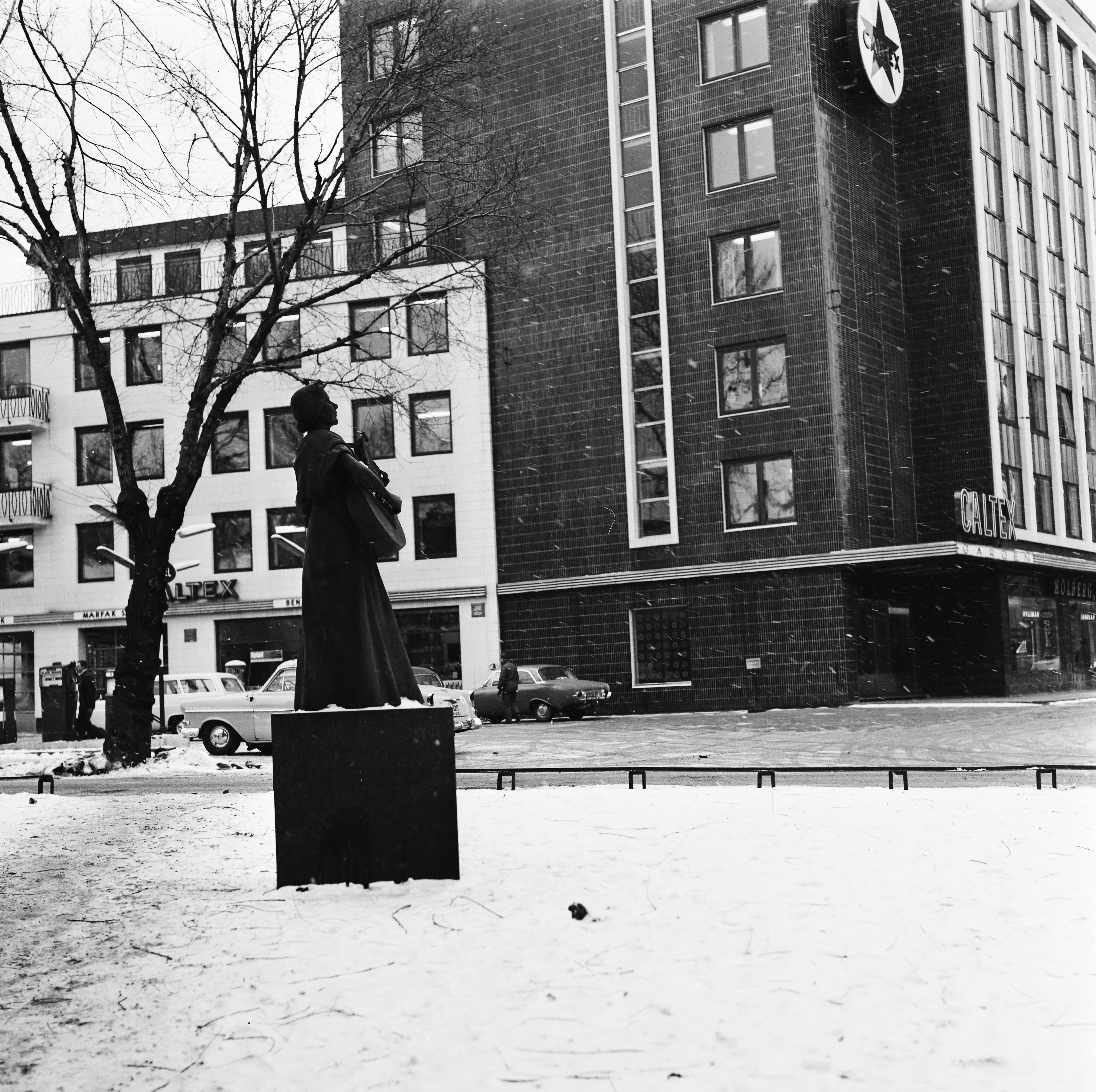 Venstre bilde er tre menn som reiser en statue av en kvinne med et strengeinstrument. H&oslash;yre bilde er samme statuen i farger og fra nyere tid