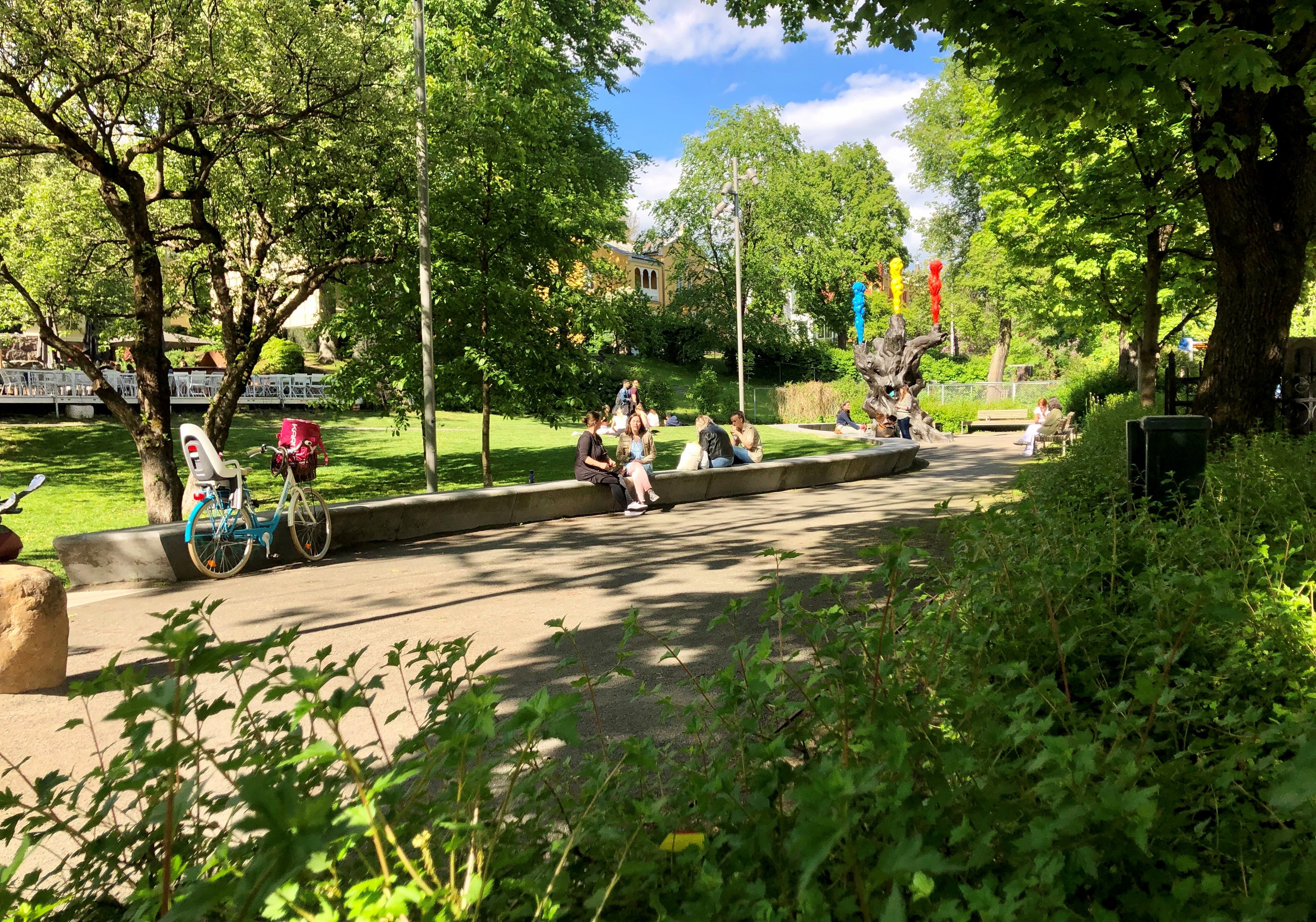 Park med mennesker som leker og sitter og snakker