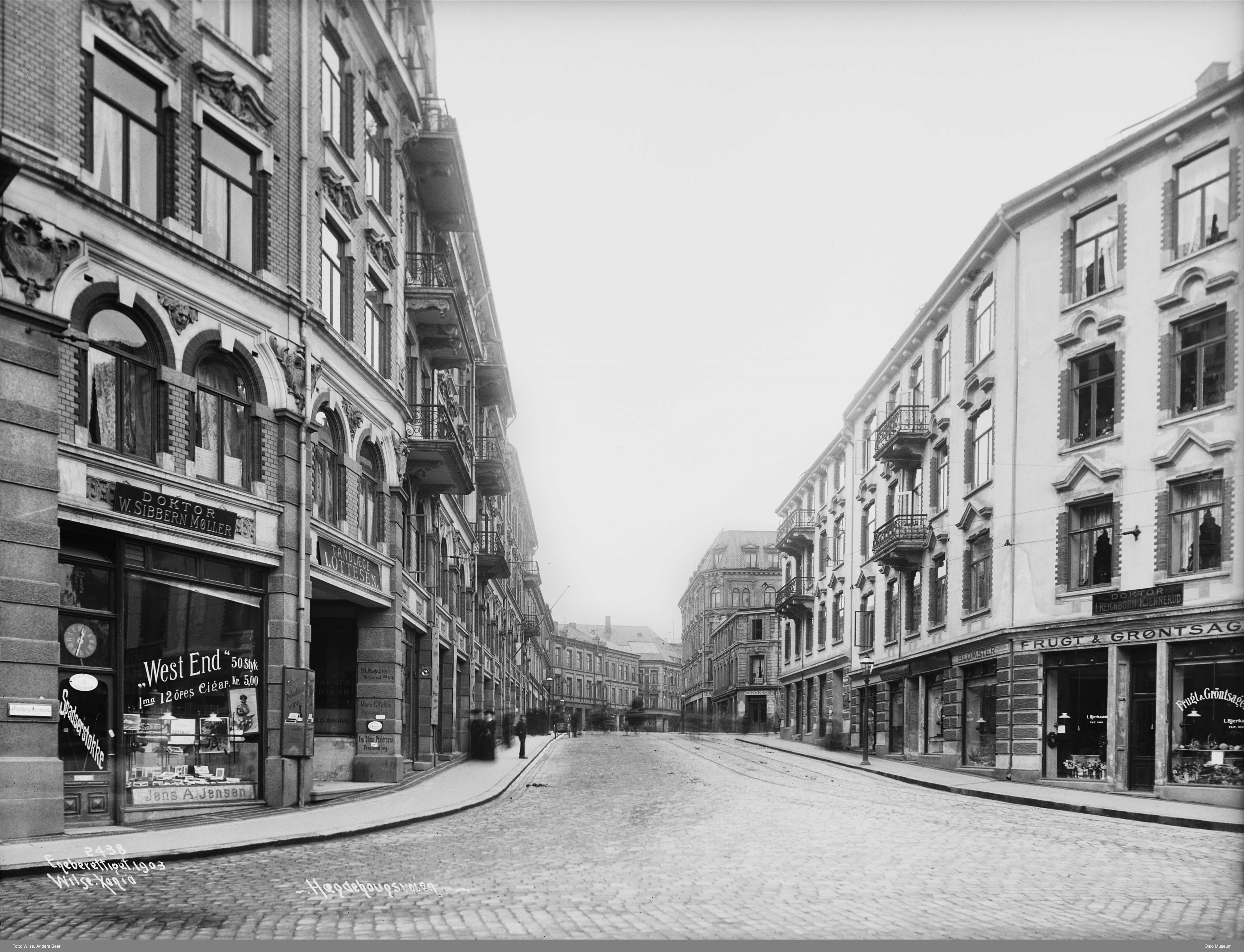 sort-hvitt av tom brosteinsgate med boligbygninger p&aring; begge sider