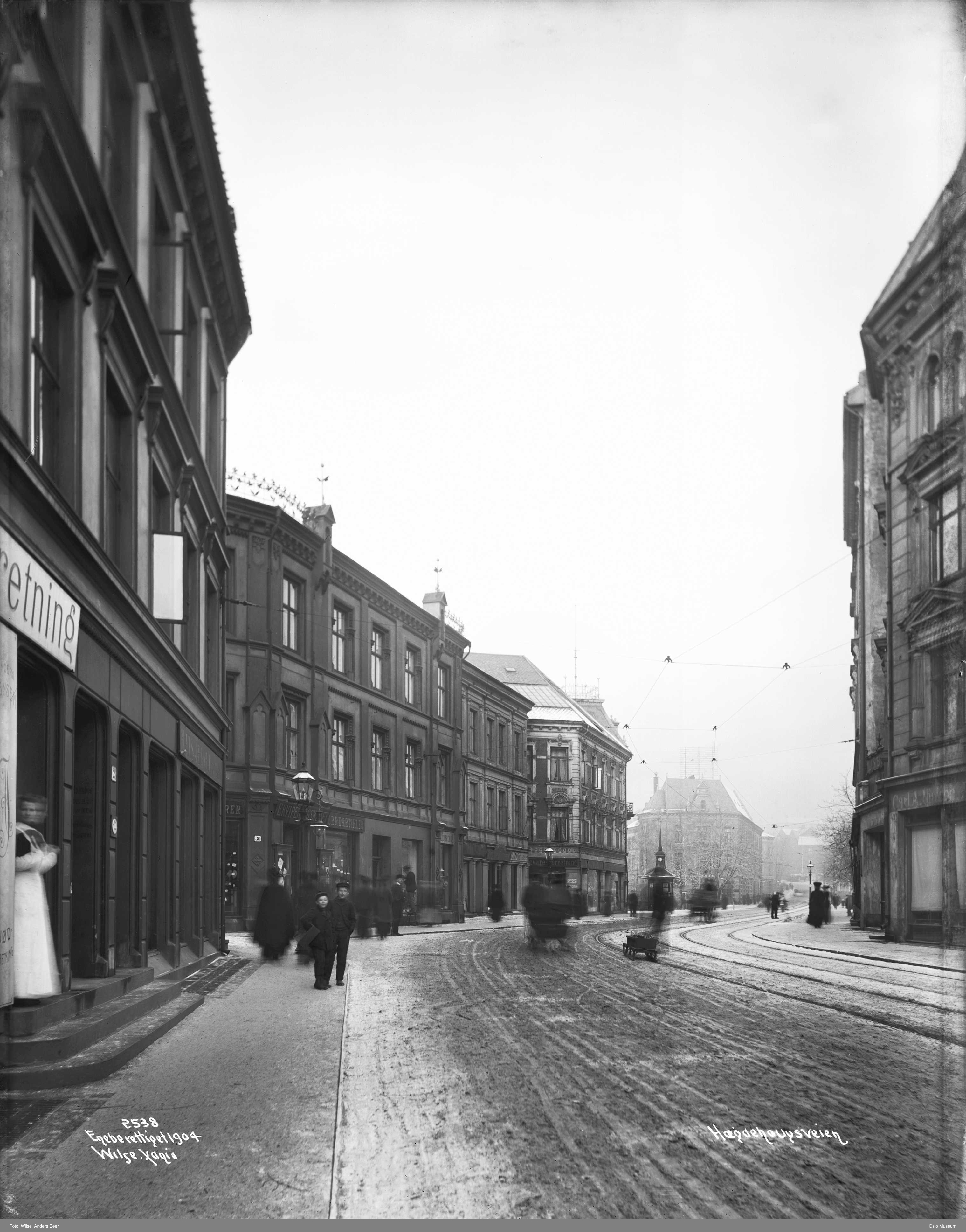 sort-hvitt av gate med mennesker og bygninger p&aring; begge sider