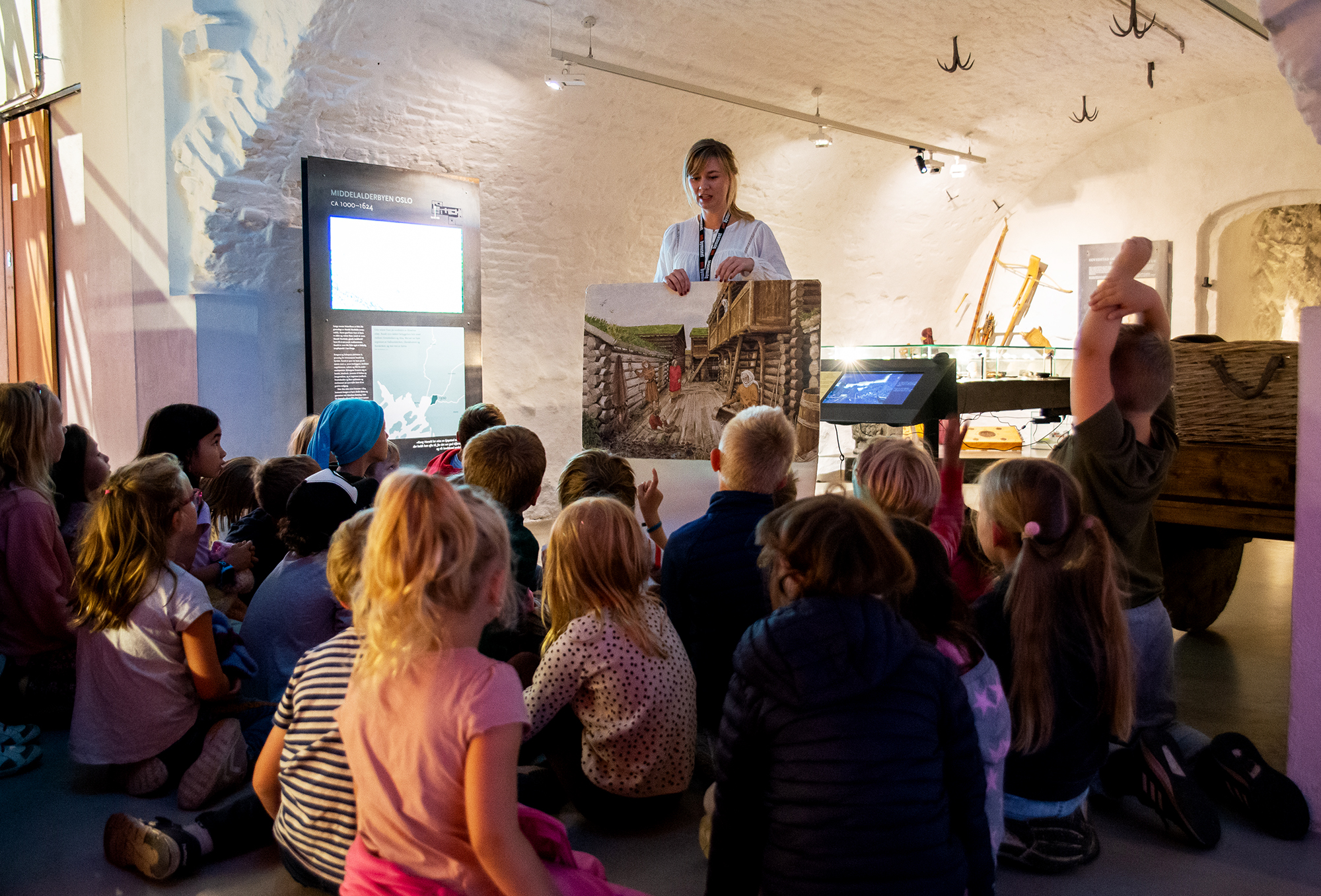 Små barn har samlet seg rundt en formidler i utstillingen