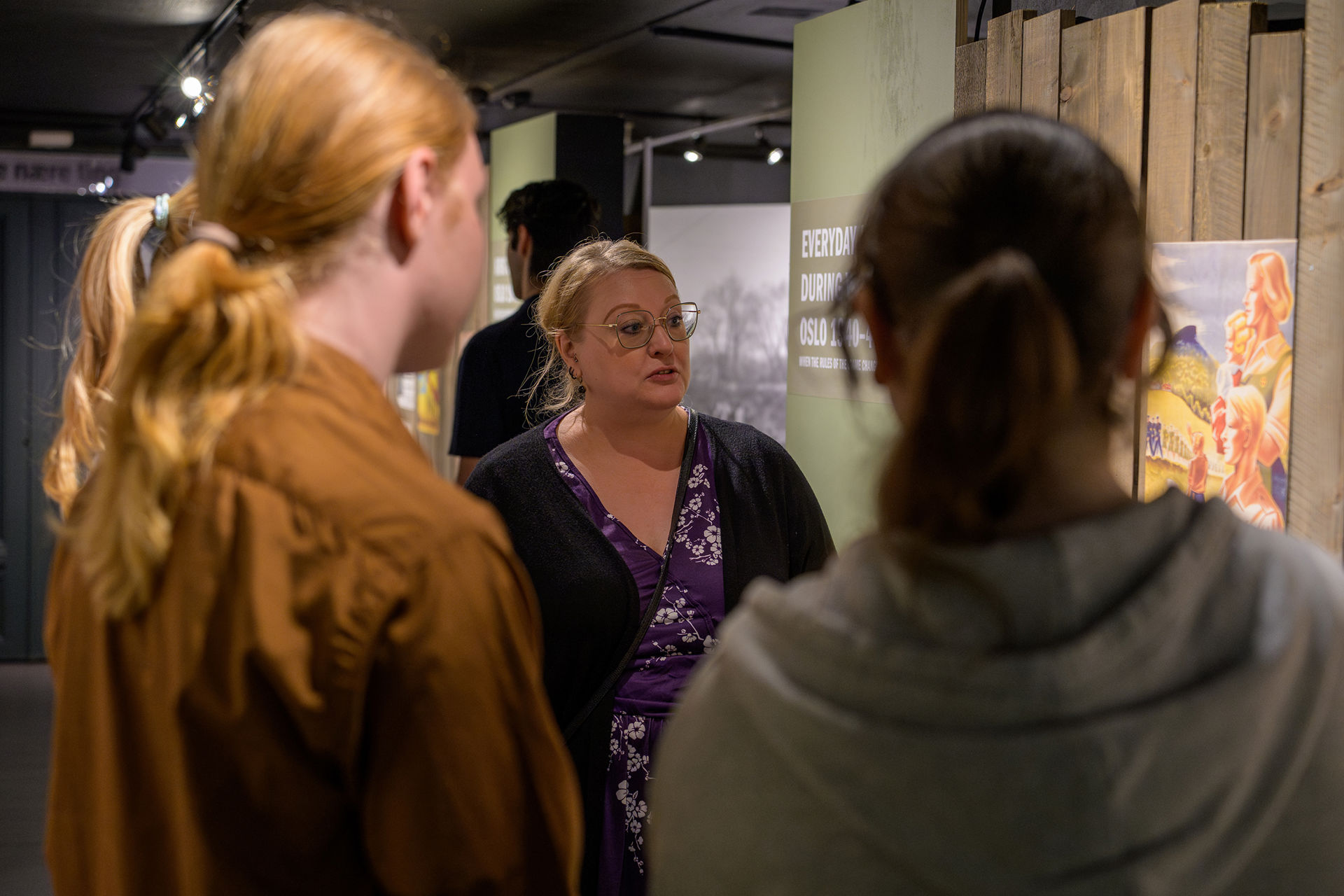 kvinne snakker til skoleelever i utstilling 