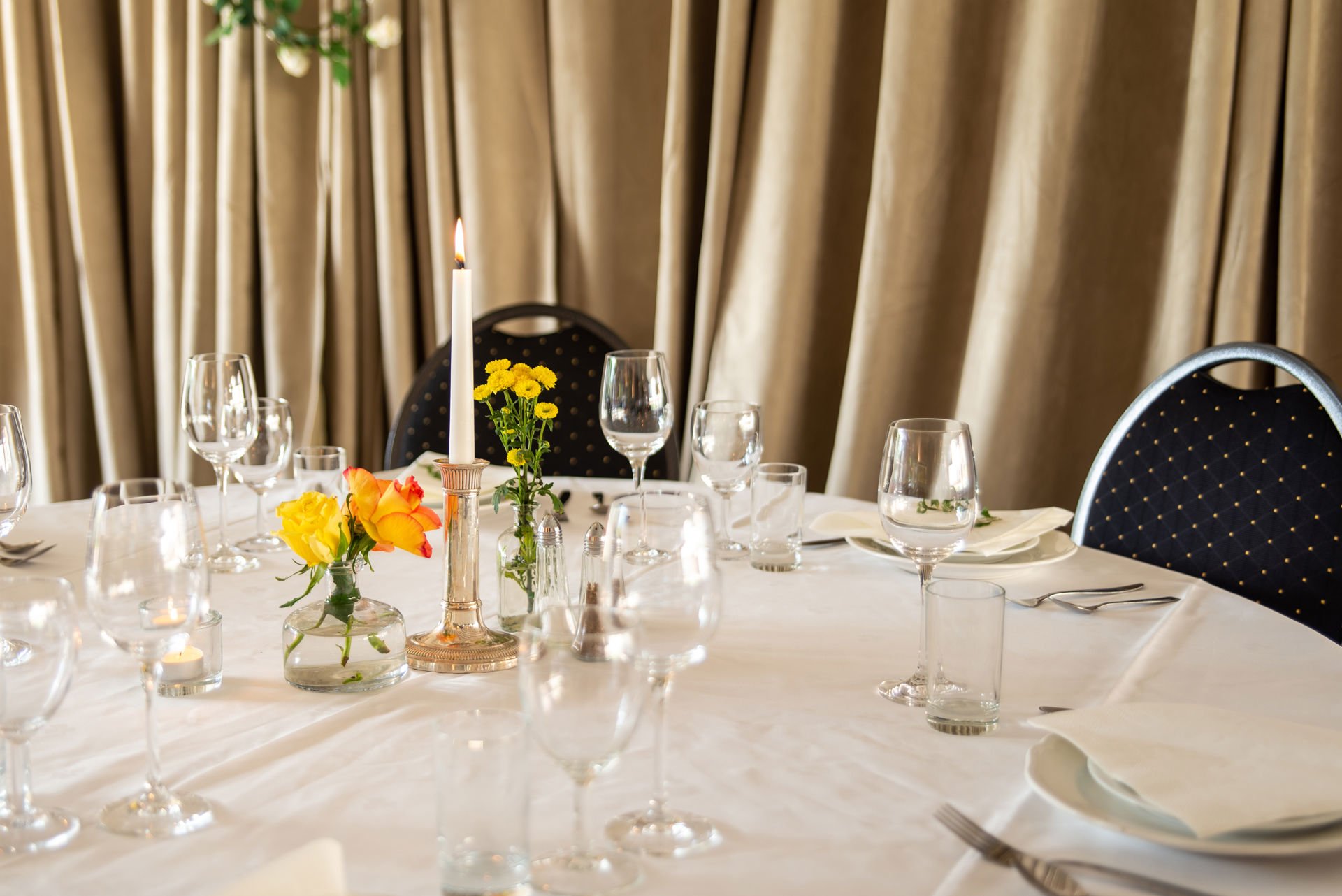 Pent oppdekket bord med hvit duk, ulike typer glass, blomster og stearinlys