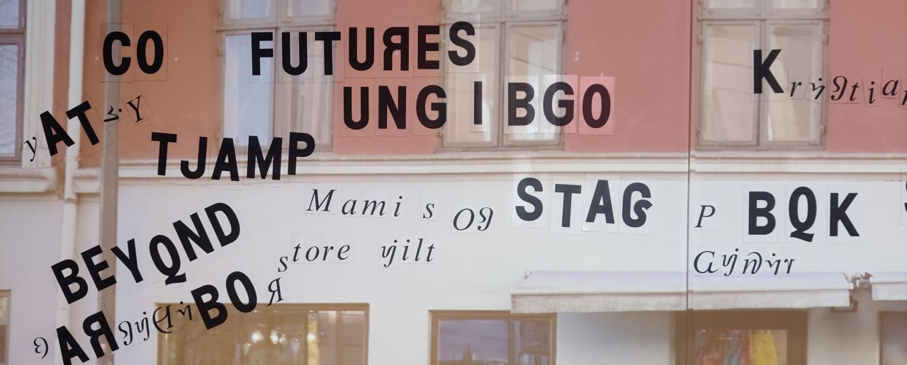 En bygningsfasade er projisert på en vegg i museet. Ord, delvis bygget opp av bokstaver som ikke eksisterer i norsk språk i dag, henger på veggen.