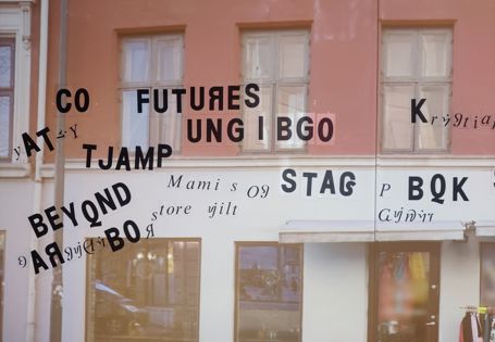 En bygningsfasade er projisert på en vegg i museet. Ord, delvis bygget opp av bokstaver som ikke eksisterer i norsk språk i dag, henger på veggen.